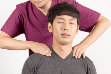 肩こりで来院した男性と施術する柔道整復師